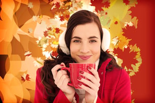 Woman in winter clothes enjoying a hot drink against autumnal leaf pattern